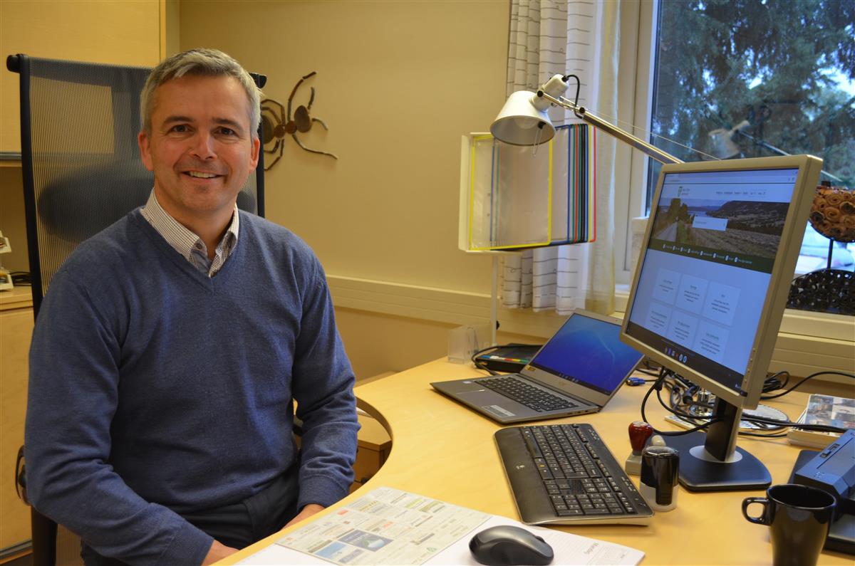 Bilde av ordfører Bror Helgestad sittende ved kontorpulten sin. - Klikk for stort bilde